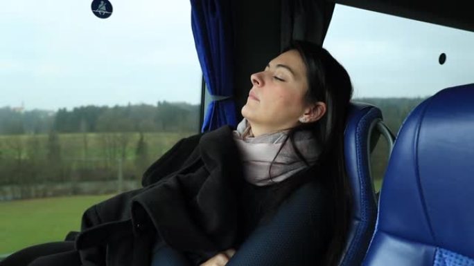 女人在乘公共汽车旅行时睡着了。女孩在公路旅行时睡觉