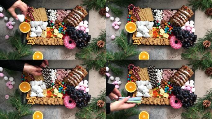 圣诞糖果拼盘。圣诞水果蛋糕，糖果，巧克力，糖果手杖，饼干，黑色托盘上的水果，顶视图。
