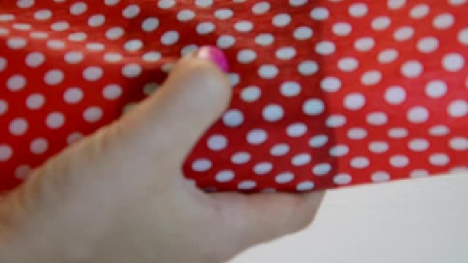 包装节日礼物，俯视图。一个不认识的女人用剪子剪的丝带和红色的包装纸包装礼品盒