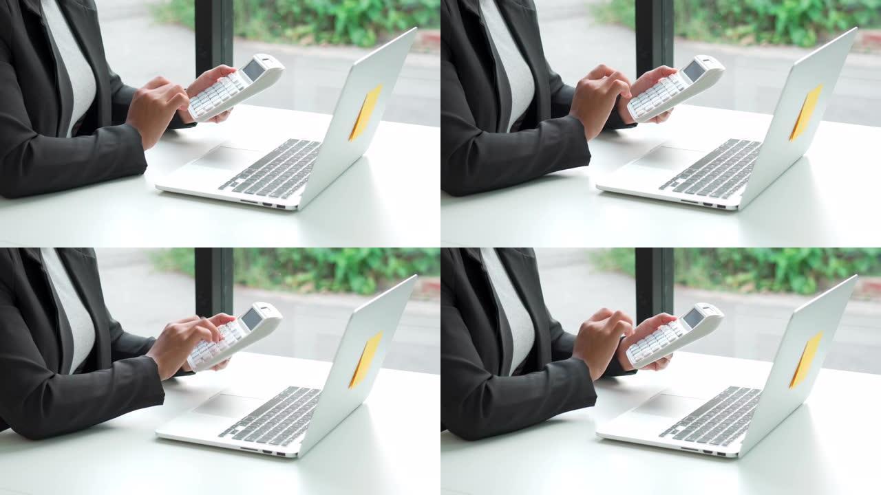 在办公室使用笔记本电脑处理财务和会计数据的计算器的商务女性的4k视频镜头