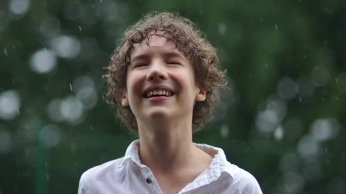 可爱的小男孩在捕捉雨滴时玩得开心的特写肖像。快乐童年少年在倾盆大雨，潮湿的季节
