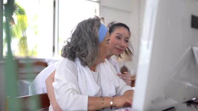 亚洲高级妇女和女儿在家中使用计算机进行视频会议