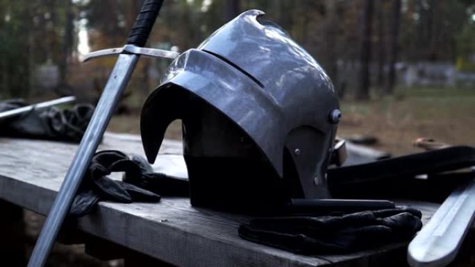 铁头盔、剑和皮手套站在木桌旁