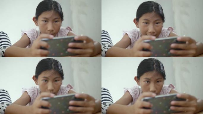 快乐的亚洲女孩玩网络游戏与她的兄弟在家里，生活方式的概念智能手机。