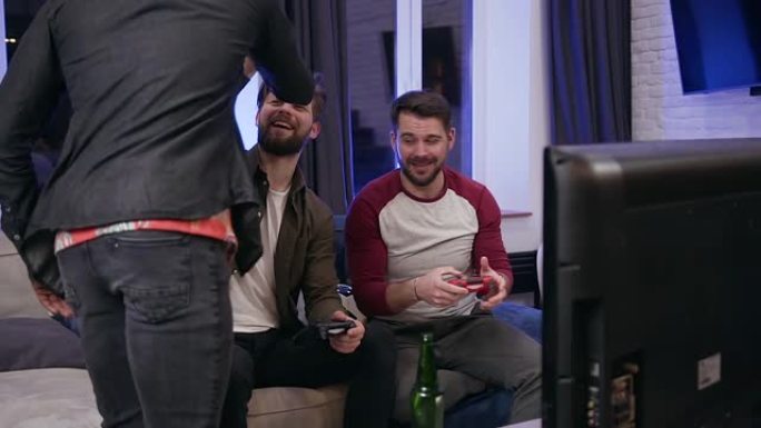 两个迷人的现代兴奋的大胡子家伙在玩电子游戏，并向他们的第三个黑皮肤的朋友击掌