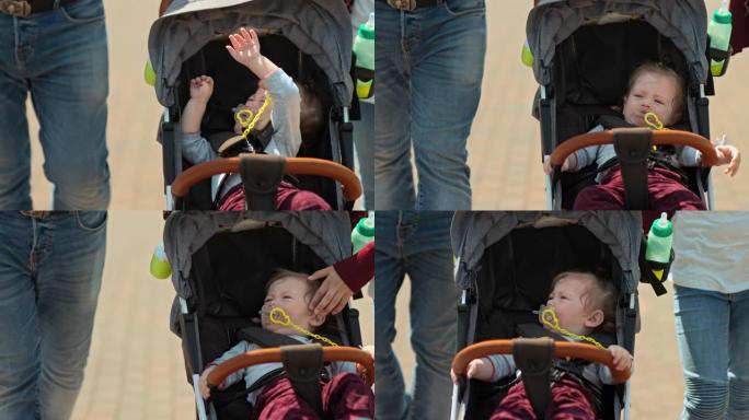 孩子在婴儿车里反复无常，嘴里吸着奶嘴。小孩被带在婴儿车里，婴儿累了，哭了。4k，10位，ProRes