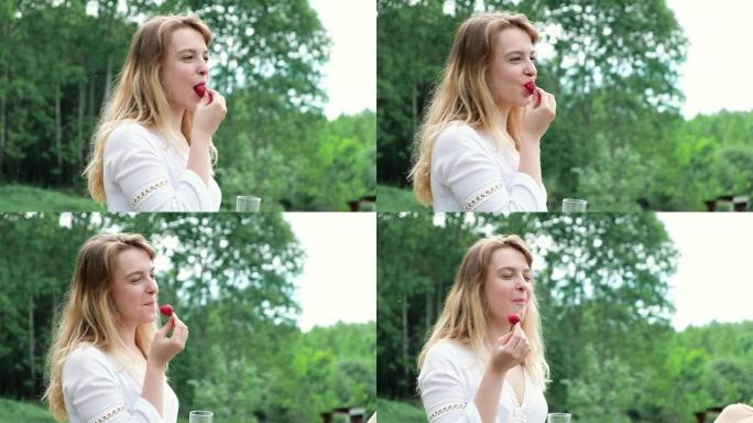 夏天野餐时，女孩在森林里咬成熟的草莓的肖像