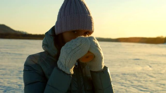 一个喝杯茶的女孩在冬天喝茶。重霜。美丽的冬天。