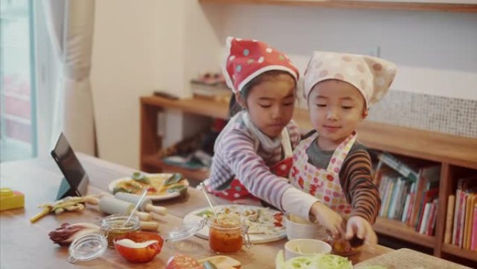 日本孩子正在学习如何在数字平板电脑上观看比萨饼的同时烹饪比萨饼