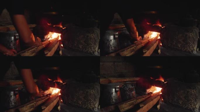 男人把木头放进火炉里开始在厨房做饭。