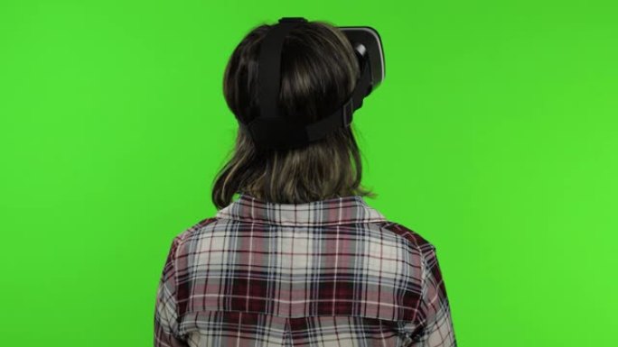 年轻女孩使用虚拟现实应用头盔玩模拟游戏。女人看虚拟现实3d视频