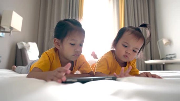 亚洲小宝宝用手机和小妹妹在卧室里晒太阳