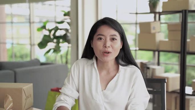 一名中年亚洲妇女正在通过视频通话打招呼，她正在通过社交媒体在线开展业务。