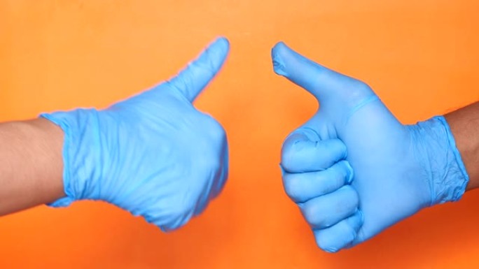 两人手持医用手套的特写镜头显示拇指向上。