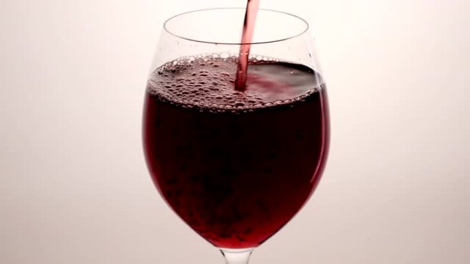 红酒从瓶中倒入白色背景的高脚杯中。将玫瑰酒倒入玻璃杯中。酒杯
