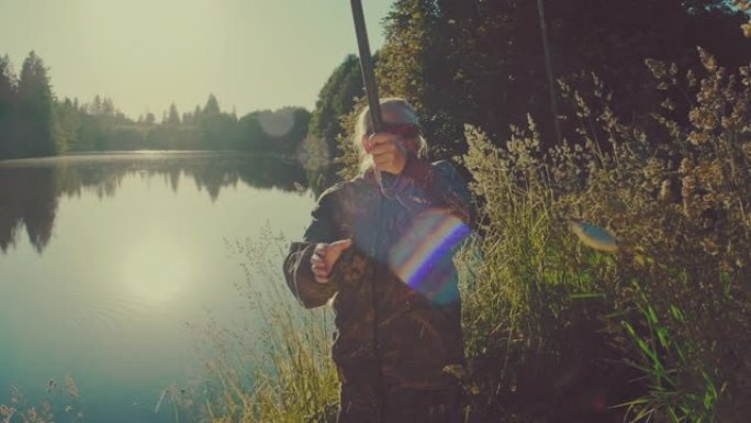 女人钓鱼。日落时在平静的夏季池塘钓鱼的老年垂钓者