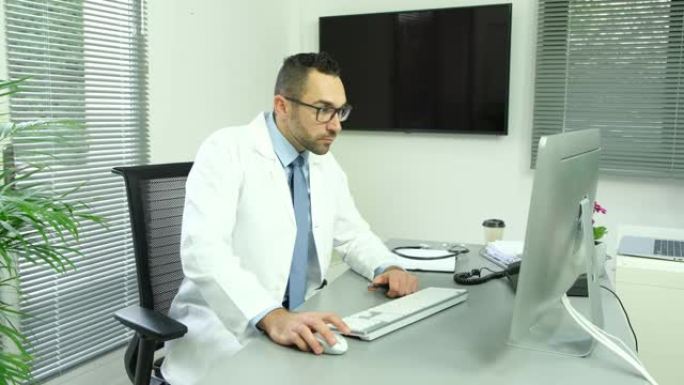 男子男医生教授科学家教师在办公桌前的医疗办公室，电脑穿着白色实验室外套研究covid19和冠状病毒
