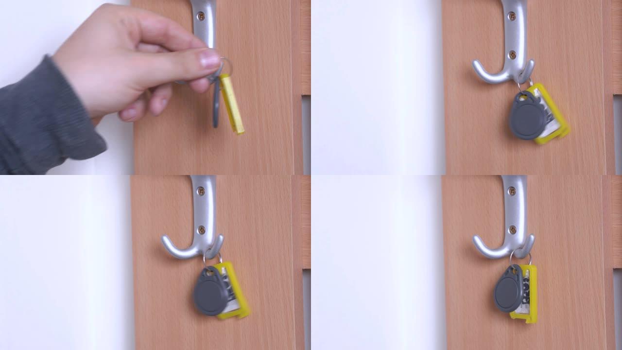 人将带有标签和铭文的磁性钥匙从酒店房间或盒子中挂在墙上的挂钩上，然后关闭。存放钥匙和各种小物品的地方