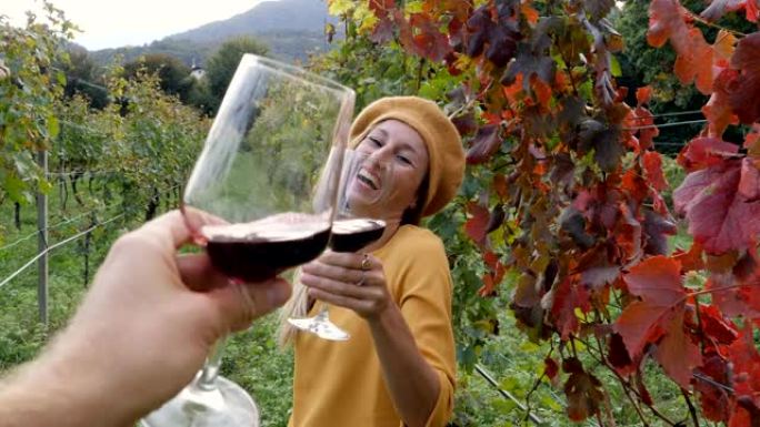 年轻夫妇在秋天的葡萄园里品尝葡萄酒