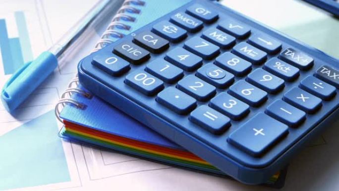 桌上蓝色计算器和财务图表的特写