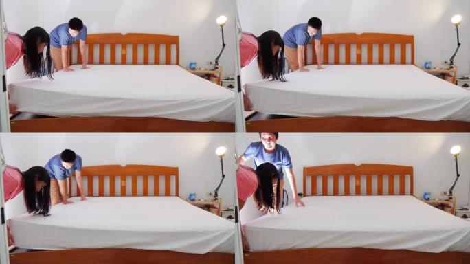 快乐的亚洲女孩和床上用品用白色床单和羽绒被与她的兄弟，生活方式的概念。