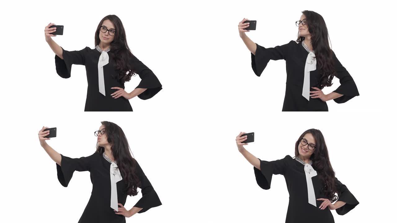 戴着眼镜的年轻白人妇女的肖像自拍，在智能手机相机上摆姿势。孤立在白色背景上。