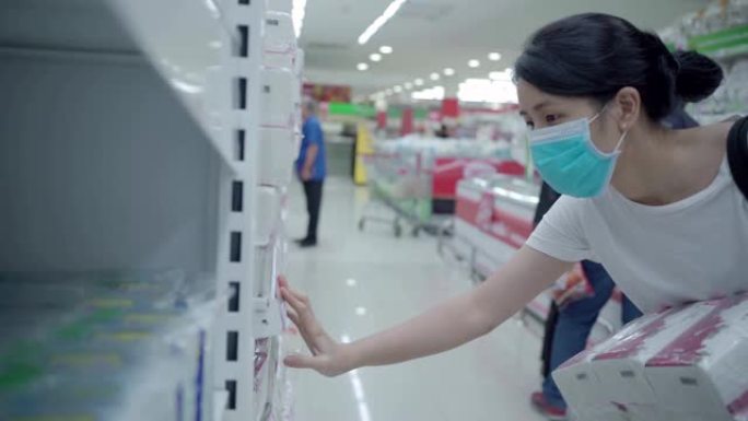 年轻的亚洲女性戴着口罩在新型冠状病毒肺炎危机期间在杂货店选择手巾纸巾，库存供应，电晕病毒大流行传播预