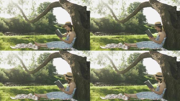 女孩在公园放松时靠在大树上。女学生花时间在公园里看书。年轻可爱的女士，戴着帽子和裙子坐在树下的草地上
