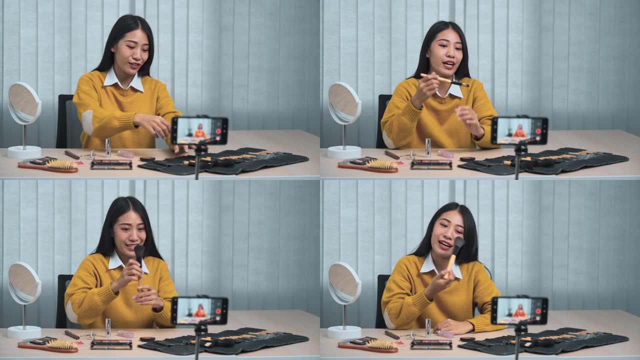 年轻的亚洲女性在家中使用手机摄像头为自己的化妆品博客制作视频，以了解美容产品。