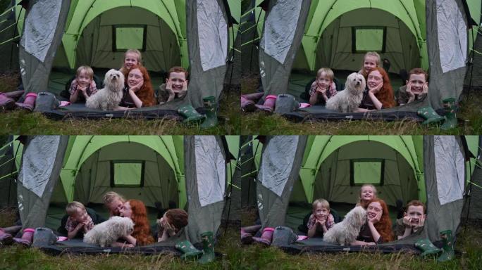 微笑的孩子和狗躺在帐篷开口内的正面