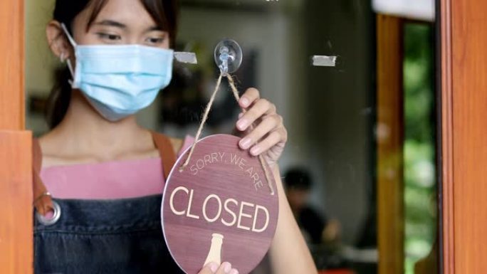 亚洲女子咖啡师老板转招牌关闭咖啡店