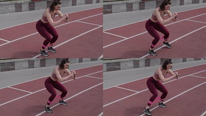 女人用粉红色的松紧带做运动，在户外的体育馆里迈出一步。