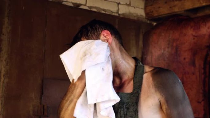 一名男性工人用白毛巾擦脸的特写镜头。