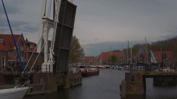 在荷兰北部荷兰历史悠久的荷兰小镇恩克赫伊森拍摄的传统荷兰运河吊桥的实时镜头开放以允许游船通过然后关闭