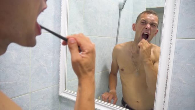 男子刷牙准备早上做卫生程序在家庭浴室的镜子里用牙刷清洁牙齿口腔护理。