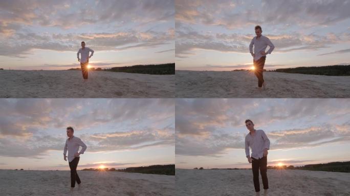 在一个美丽的夏日傍晚，年轻的沉思男子赤脚走在沙滩上。情绪。慢动作镜头。万向节射击