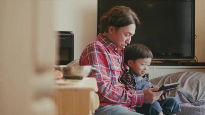 父亲在数字平板电脑上观看动画片时与孩子们在一起