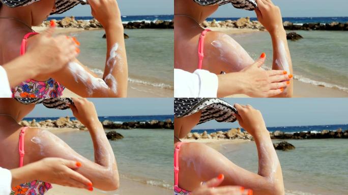 特写，在肩膀和手臂的皮肤上涂抹防晒霜或喷雾乳液。在烈日下的海滩上，在大海的背景下。防晒和防紫外线。皮