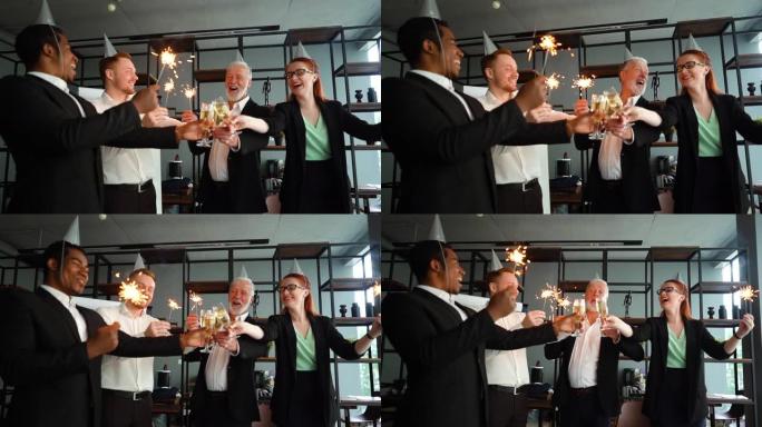 由多种族同事组成的商业团队，他们手持孟加拉灯，碰杯香槟。