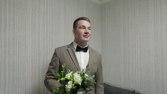 新郎手里拿着婚礼花束在家里。白色衬衫，夹克
