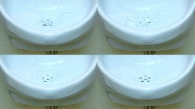 从陶瓷小便池流向马桶孔的水的特写视图。