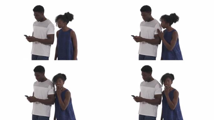 好奇的黑人女孩偷窥手机打字的肖像她的非洲男友孤立在白色背景上