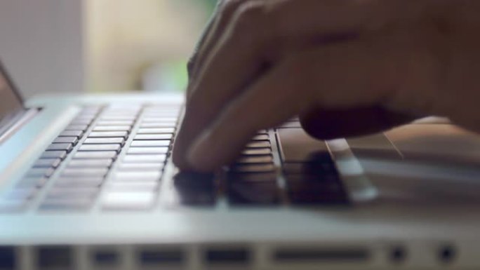 4kclose up Man hands在家里工作的笔记本电脑键盘上打字。手触摸打字键盘使用inte