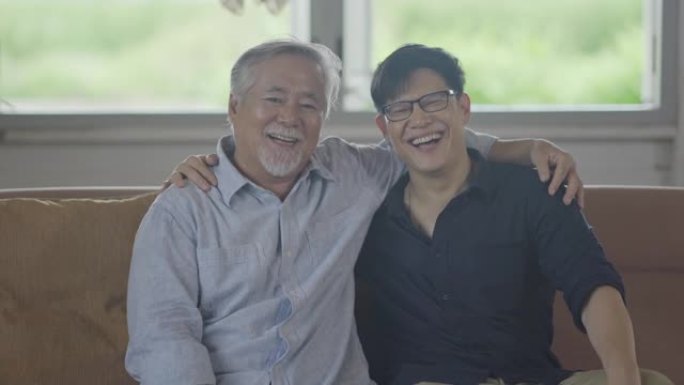 微笑亚洲父亲和大儿子呆在家里一段时间的检疫和社交距离