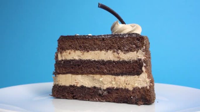 漂亮的巧克力蛋糕。在蓝色背景上的盘子上旋转。示范。