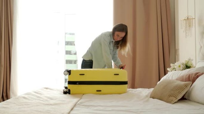 女人正在酒店房间里收拾黄色手提箱