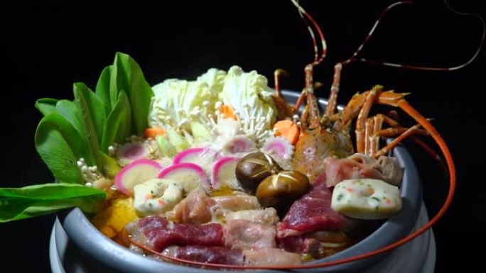 寿喜烧多刺龙虾与蔬菜和肉类一起在火锅中食用，多刺龙虾Nabe，用筷子将肉放入火锅中。