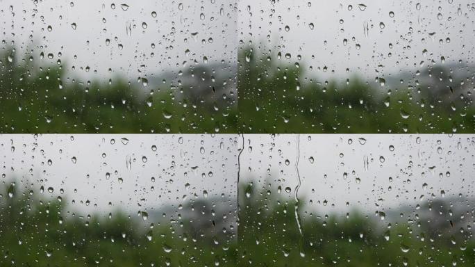 强烈的雨水冲向窗户玻璃并流下来。特写。雨季玻璃背景上的雨滴