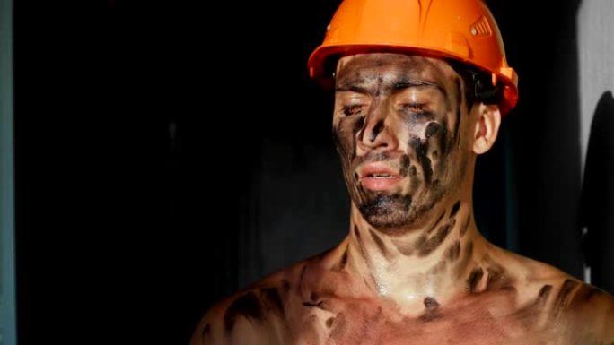 肖像肮脏累了下班后建筑工人在阳光下。戴着安全帽的白人英俊严肃的男人。肮脏的工作和体力劳动。工作设备的