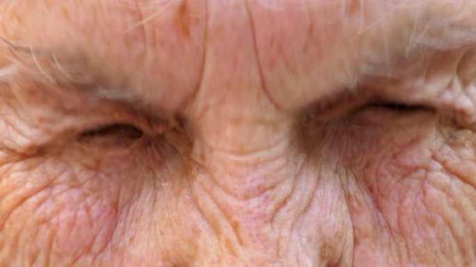成熟祖母的肖像以惊人的面部表情看着镜头。奶奶的特写强烈地拧了她灰色的眼睛。皱纹成熟的女性脸上显示出惊